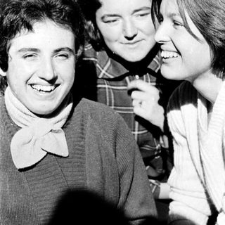Three people smiling and laughing together indoors.
