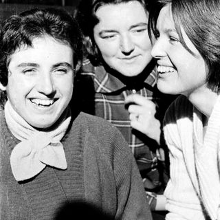 Three people smiling and laughing together indoors.