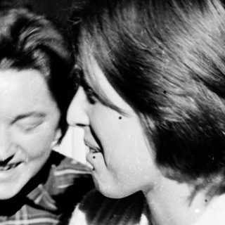 Two people laughing together indoors.