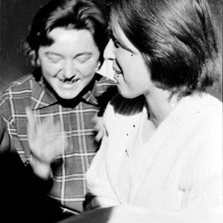 Two people laughing together indoors.