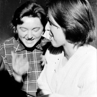 Two people laughing together indoors.