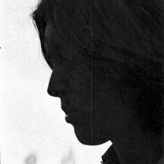 Silhouette of person with short hair outdoors.