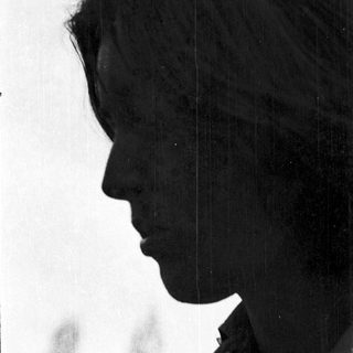 Silhouette of person with short hair outdoors.