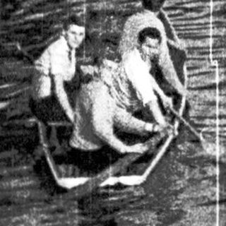 People rowing a small boat on a lake.