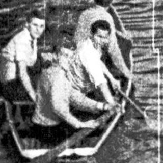 People rowing a small boat on a lake.