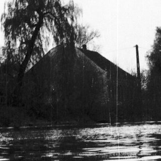 Flooded landscape with house partially submerged in water.