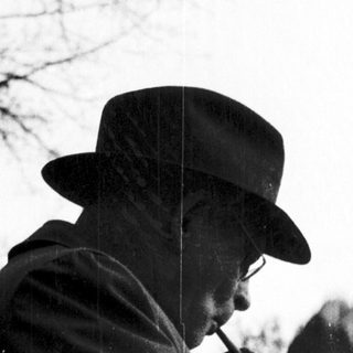 A man in outdoor attire smoking a pipe.
