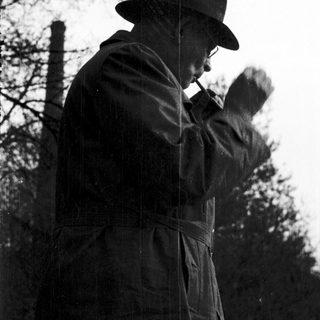 A man in outdoor attire smoking a pipe.
