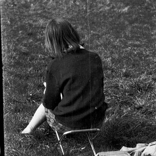 Person sitting alone on grass in outdoor setting.