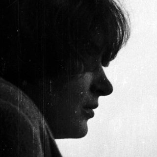 Person gazing thoughtfully outside rainy window.