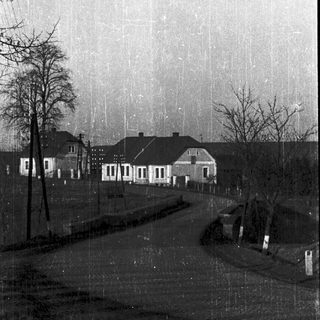 Rural street scene with rain-soaked houses and trees.