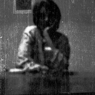 Silhouette of person sitting alone in rain.
