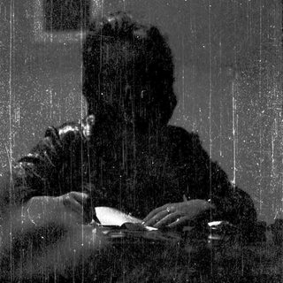 Silhouette of person reading indoors during rain.