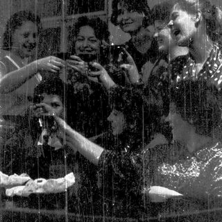 Group celebrating indoors during heavy rain.