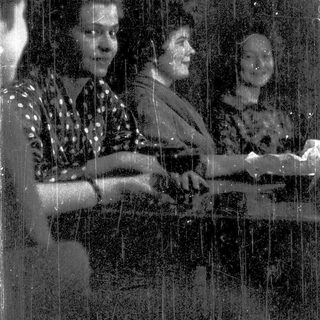 Three people playing piano together indoors.