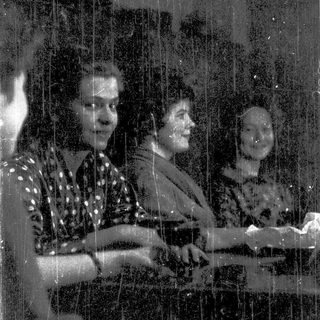 Three people playing piano together indoors.