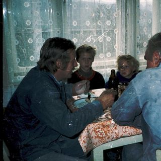 Family gathering around a table eating indoors.