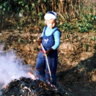 Person composting garden waste with smoking pile.