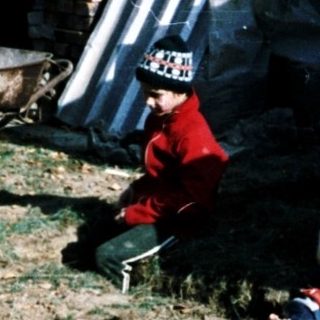 Two children playing outside near construction materials.