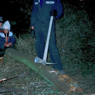 Children sitting near a nighttime campfire with adult nearby.