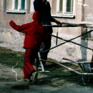 People painting and repairing a weathered house exterior.