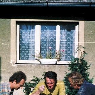 Three men sitting outdoors at a table.