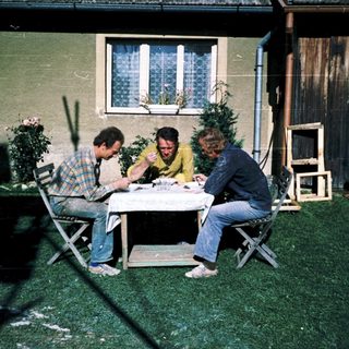 Three men sitting outdoors at a table.