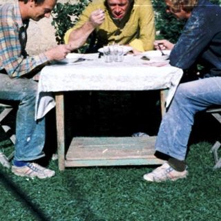 Three men sitting outdoors at a table.