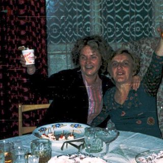 Celebratory gathering with cake, glasses, and smiling women.
