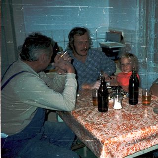 Family gathering indoors with drinks at a table.
