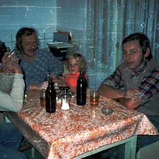 Family gathering indoors with drinks at a table.