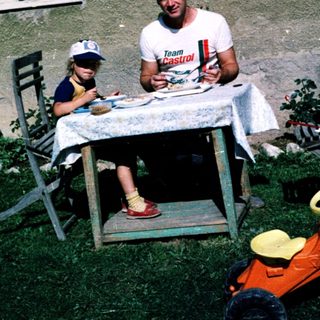 Family picnic outdoors near a house.