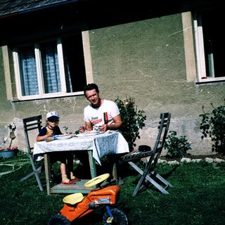 Family eating outdoors near a house.