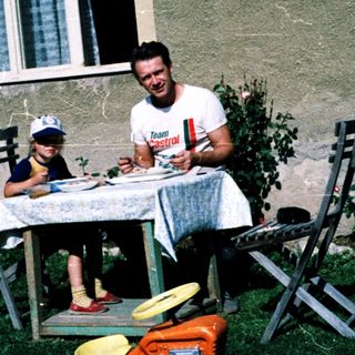 Family eating outdoors near a house.