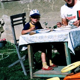 Family eating outdoors near a house.