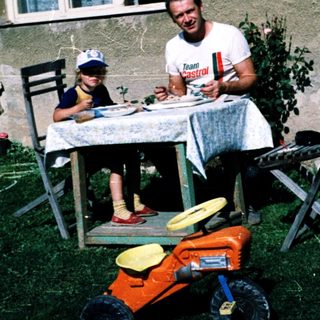 Family eating outdoors near a house.