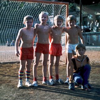 Five children posing near a soccer goal.