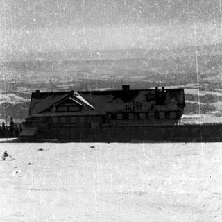 Large chalet-style building on snowy mountain landscape.