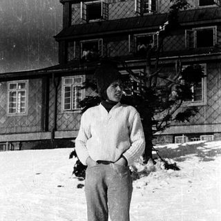 Person standing in snowy outdoor setting near building.