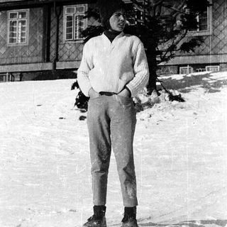 Person standing in snowy outdoor setting near building.
