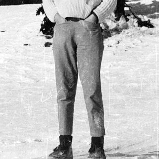 Person standing in snowy outdoor setting near building.