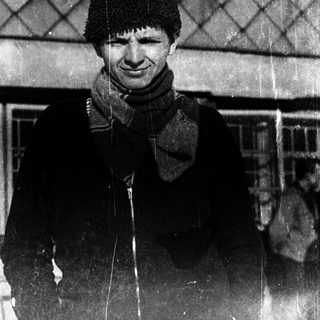Young man wearing winter hat and scarf outdoors.