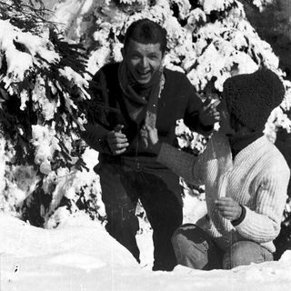 Two men skiing in snowy terrain, posing happily.