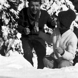 Two men skiing in snowy terrain, posing happily.
