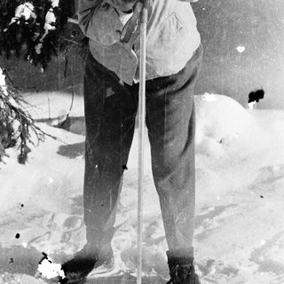 Woman skiing in snowy forest, holding poles.