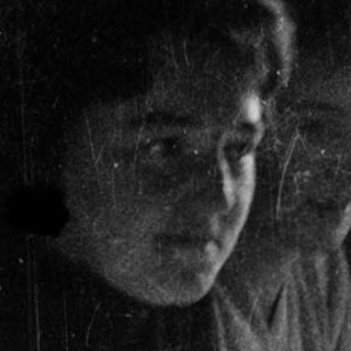 Two people sitting indoors near a window, another person standing outside in rain.
