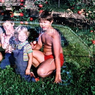 Family posing among lush green grass and apple trees.