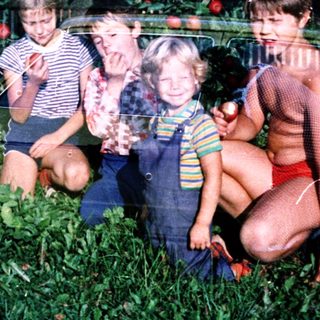 Family posing among lush green grass and apple trees.