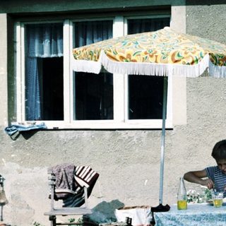 Two children eating outdoors under umbrella.