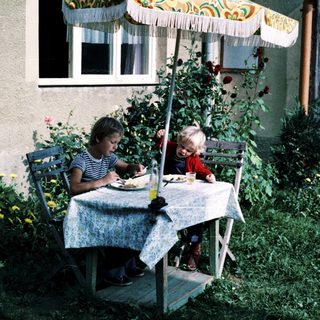 Two people eating outdoors under umbrella.